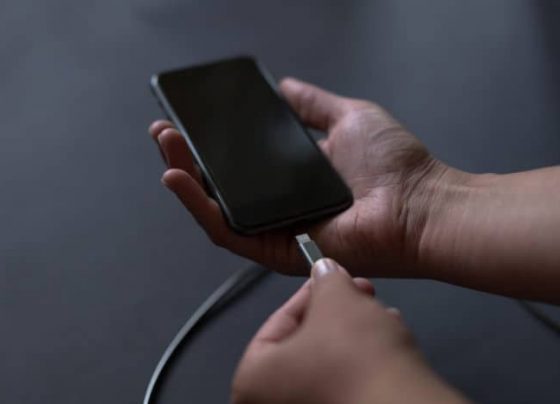 Φωτογραφία ενός ανθρώπινου χεριού να συνδέει το φορτιστή με το κινητό.